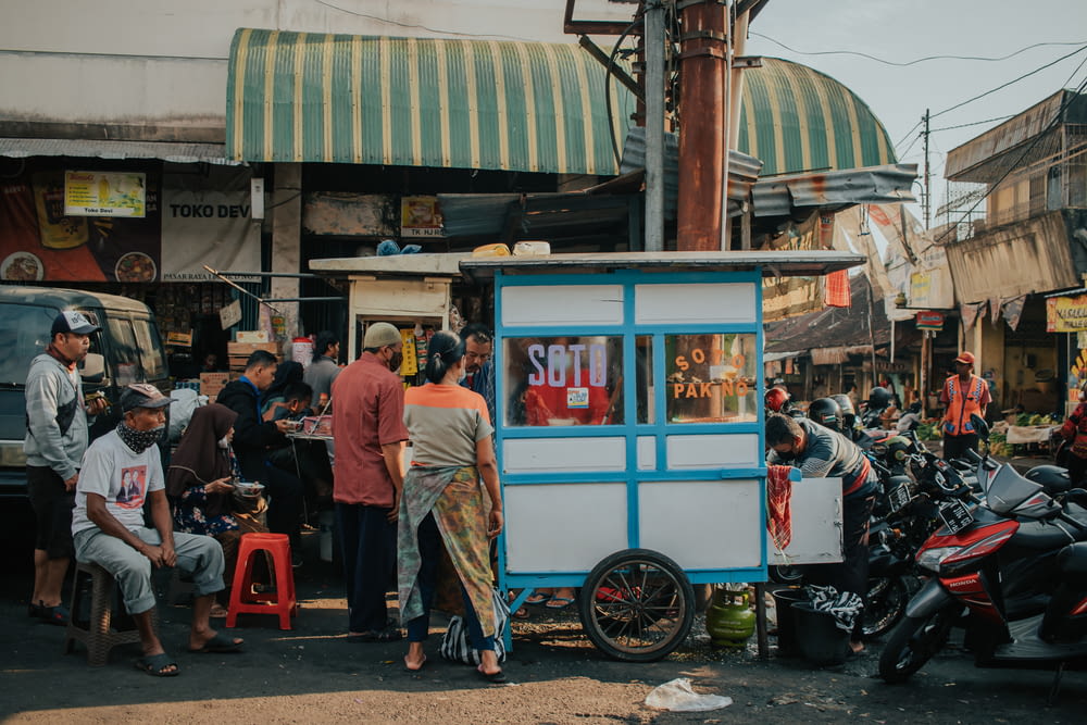 people standing near blue and white food stall during daytime