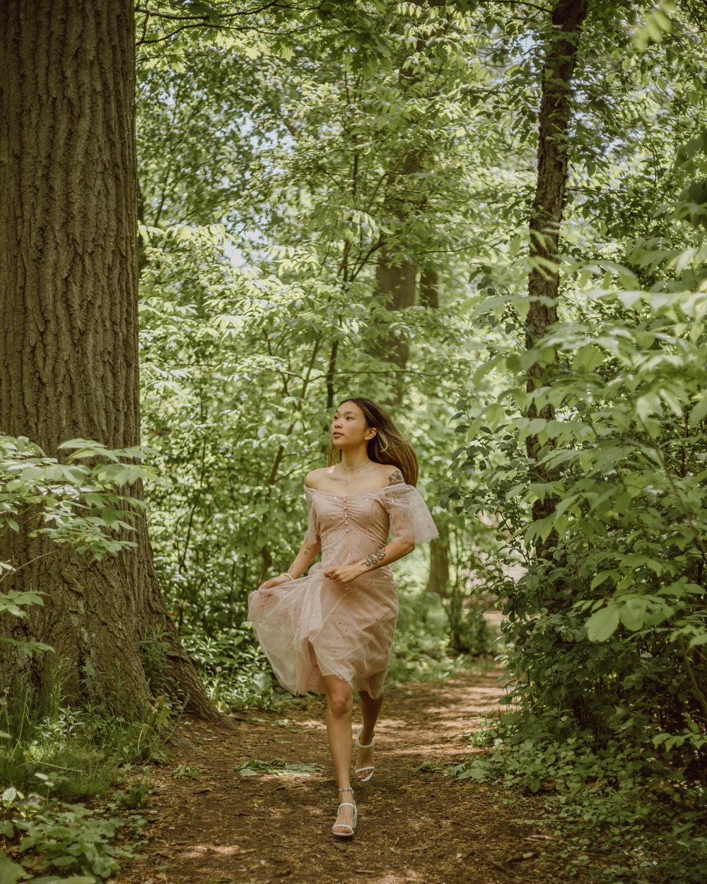 woman in beige dress standing beside tree