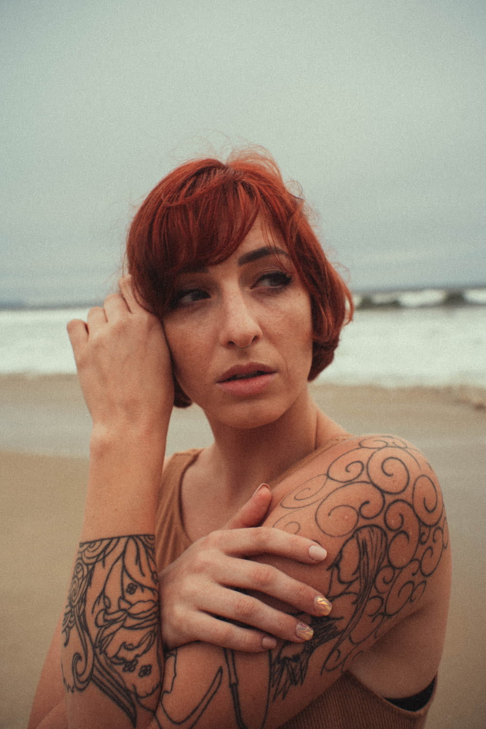 a woman with red hair and tattoos on her arm