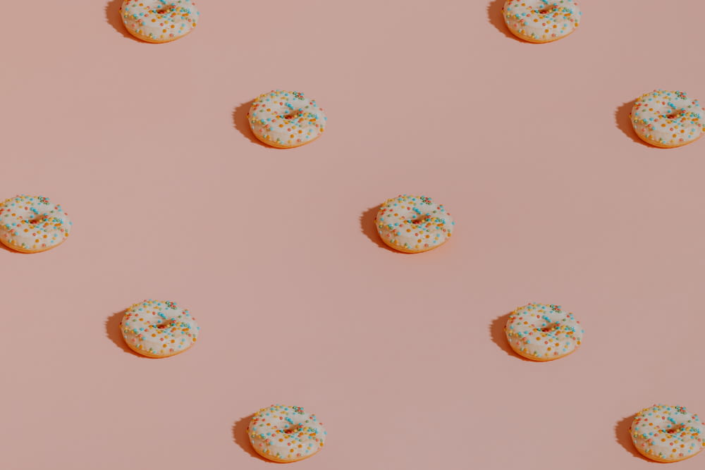 a pattern of donuts with sprinkles on a pink background
