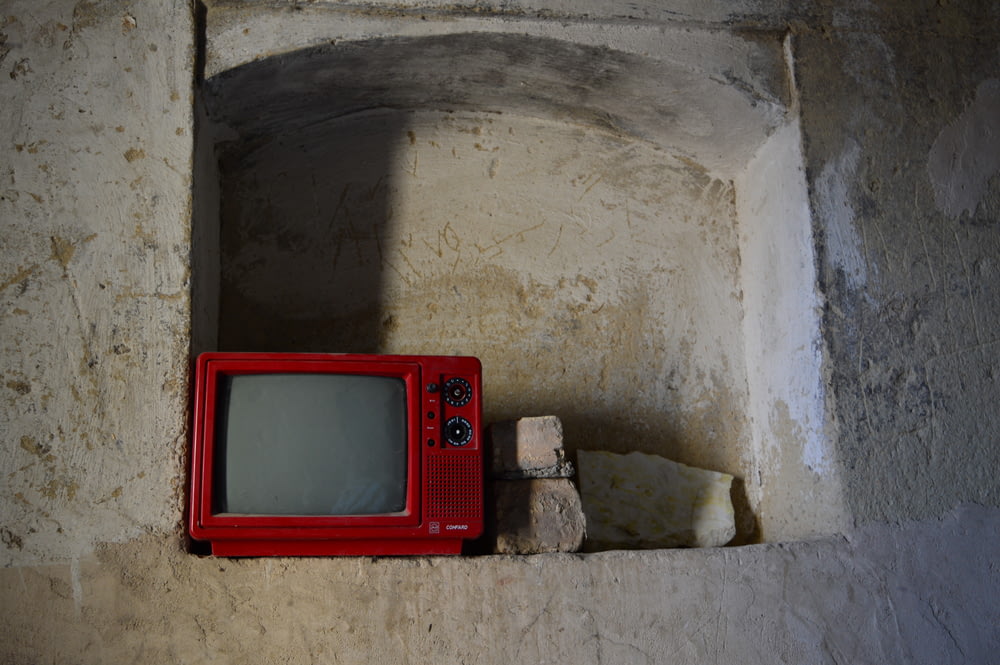 a red tv sitting on top of a stone wall