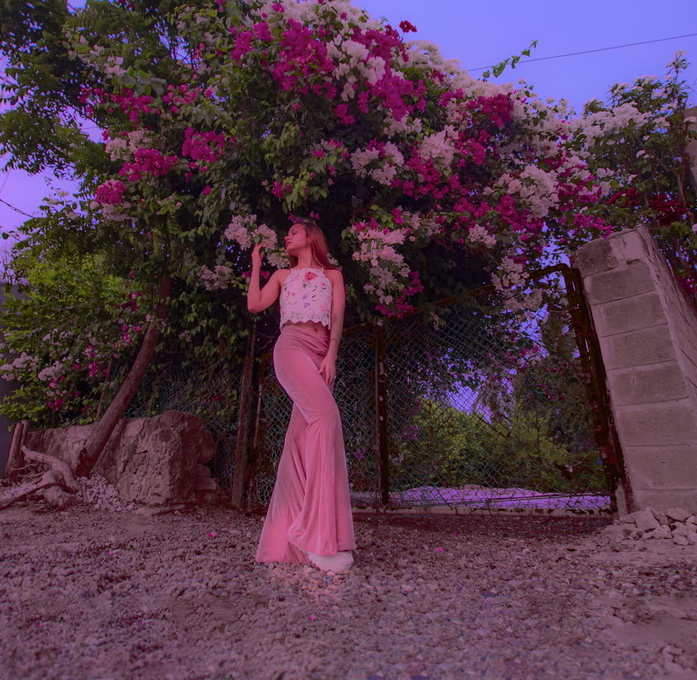 woman in pink dress standing near brown concrete wall during daytime