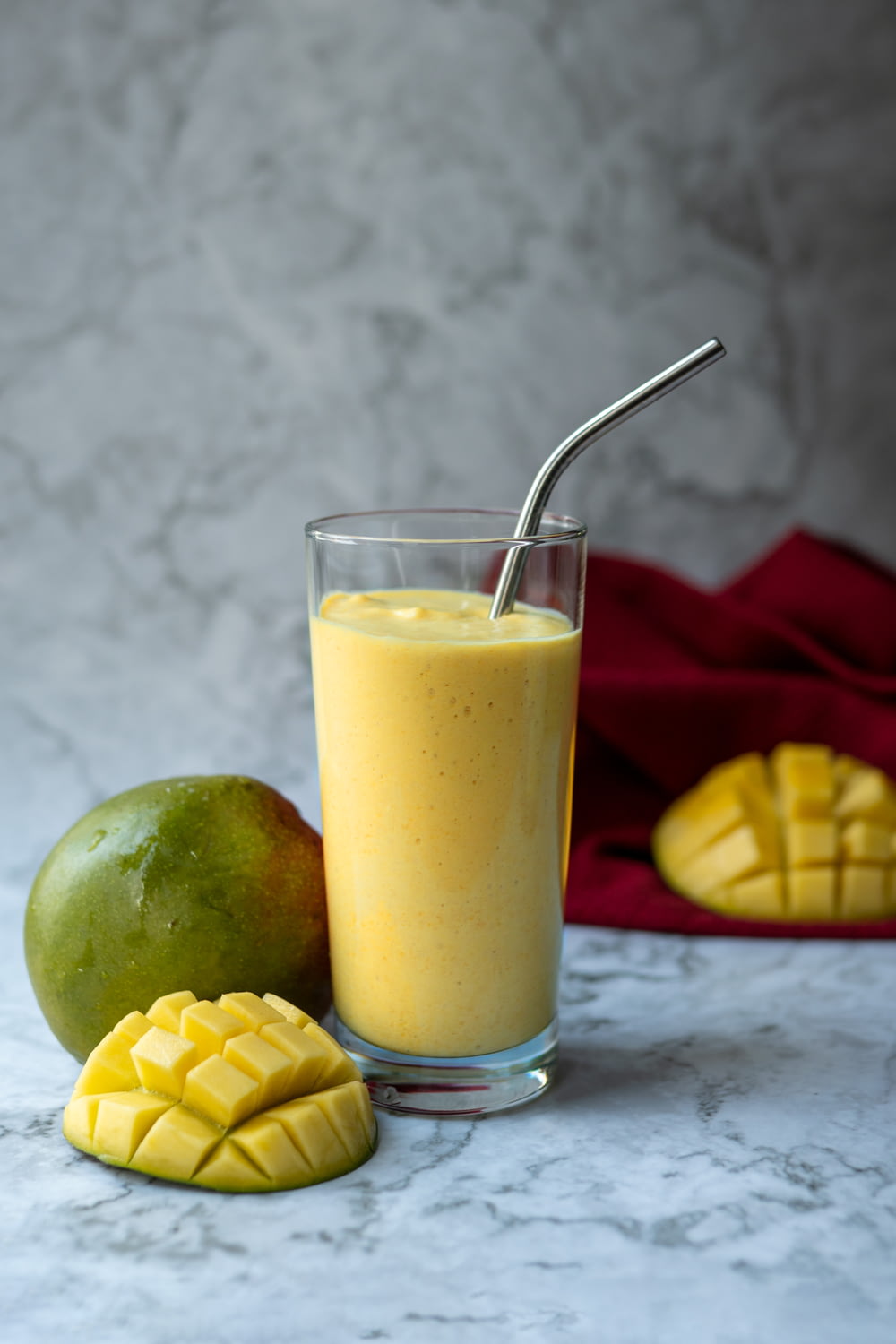a glass filled with a smoothie next to a mango