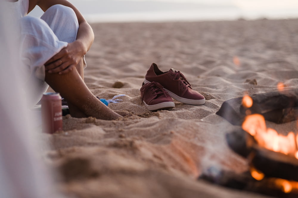 a person sitting on a beach next to a campfire