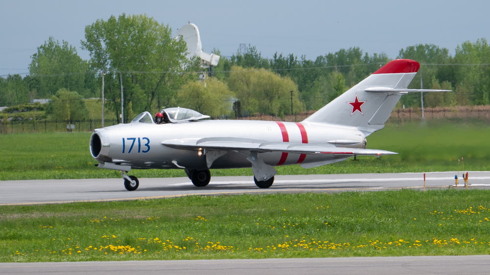 a silver and red jet sitting on top of a runway