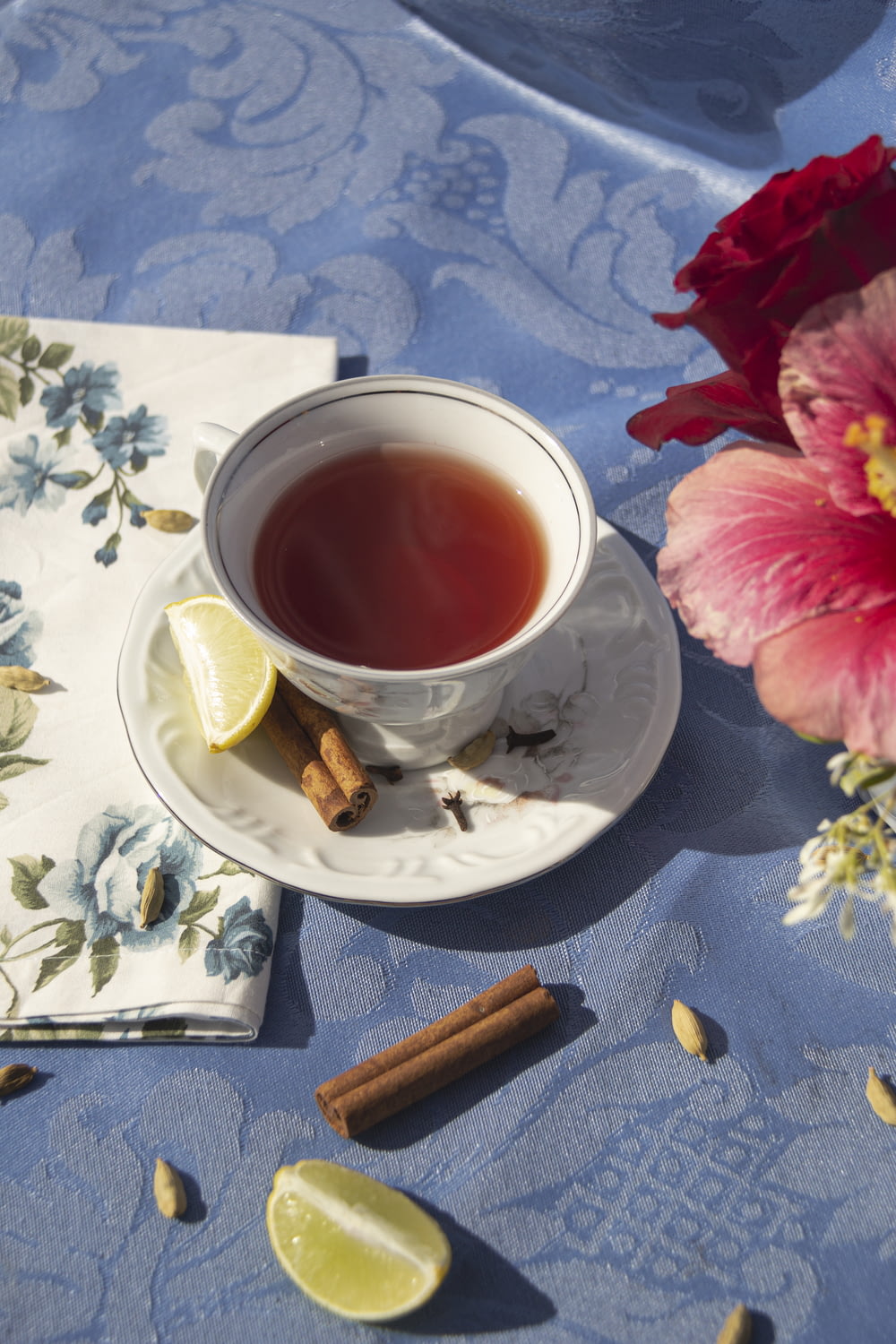 a cup of tea next to a napkin and a flower