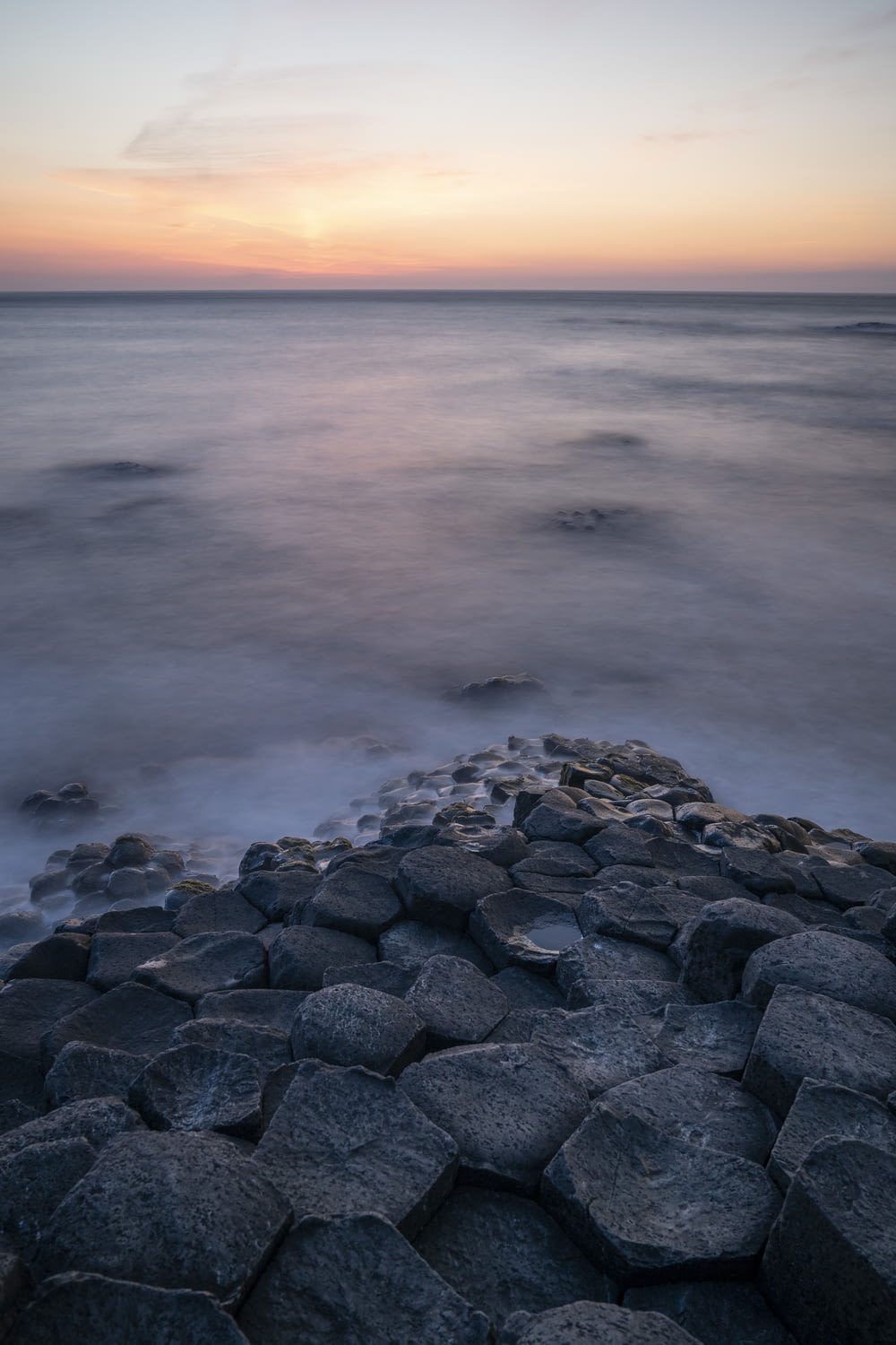 une plage rocheuse avec des rochers au premier plan et un coucher de soleil en arrière-plan