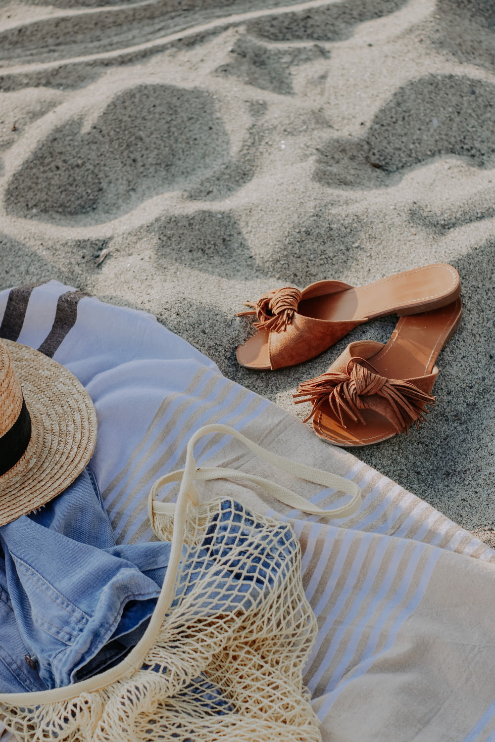 a hat and a pair of sandals on a beach