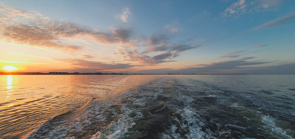 the sun is setting over the water as seen from a boat