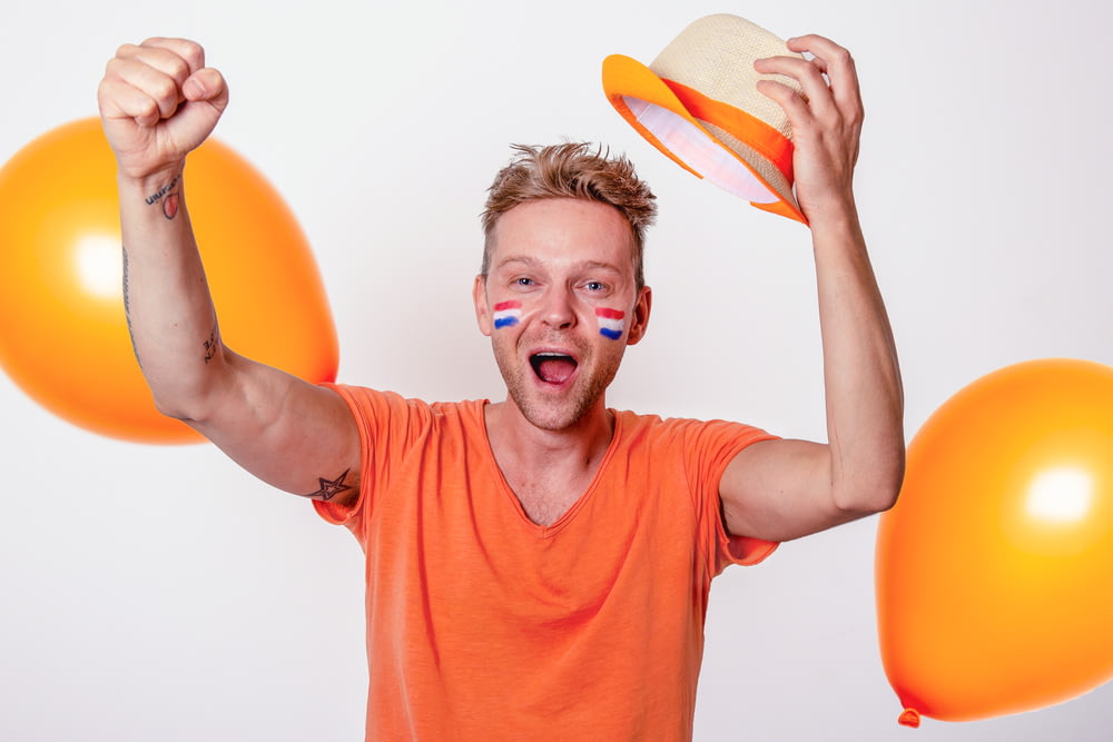 a man is holding balloons and a hat