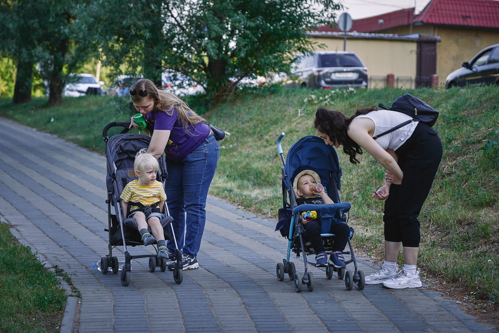 a woman pushing a stroller with two children in it