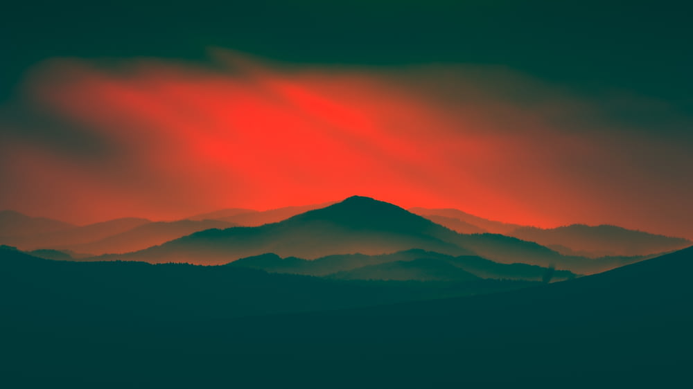 a red and green sky over a mountain range
