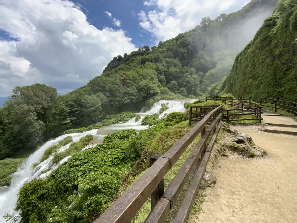 a wooden fence overlooks a waterfall in the mountains
