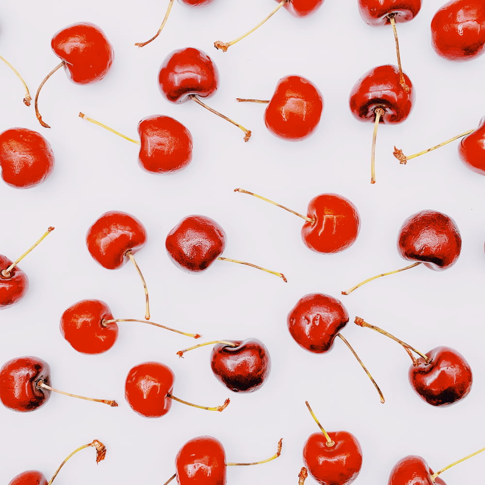 frutos rojos redondos sobre superficie blanca
