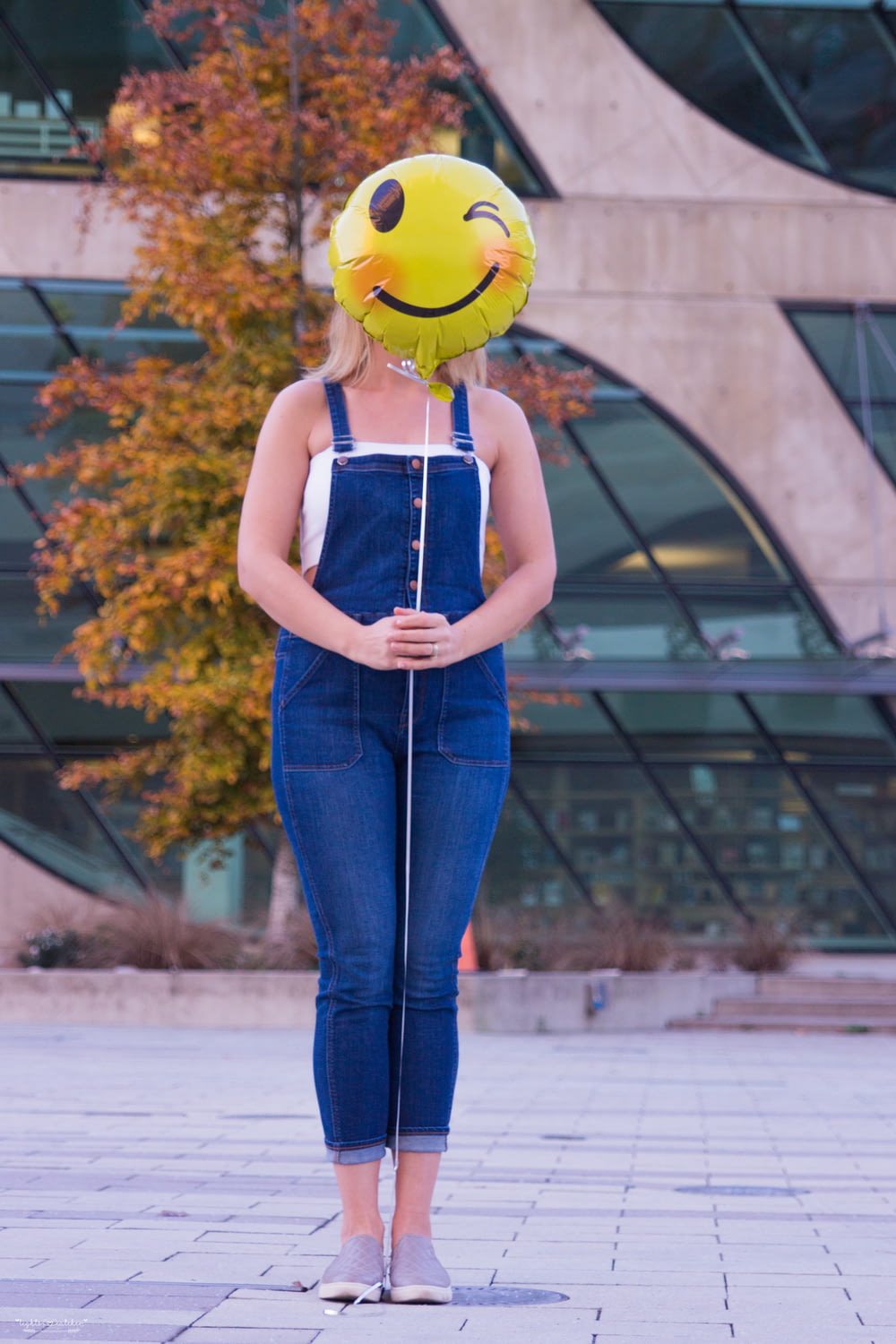 woman in blue denim jeans with yellow hat standing near brown leaf trees during daytime