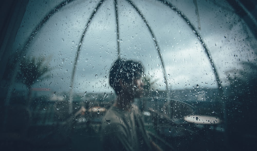 a person standing in front of a rain covered window