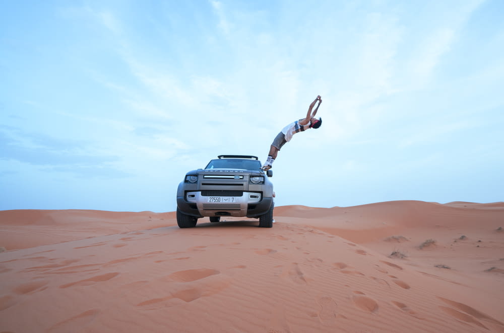 a man doing a handstand on the back of a truck in the desert