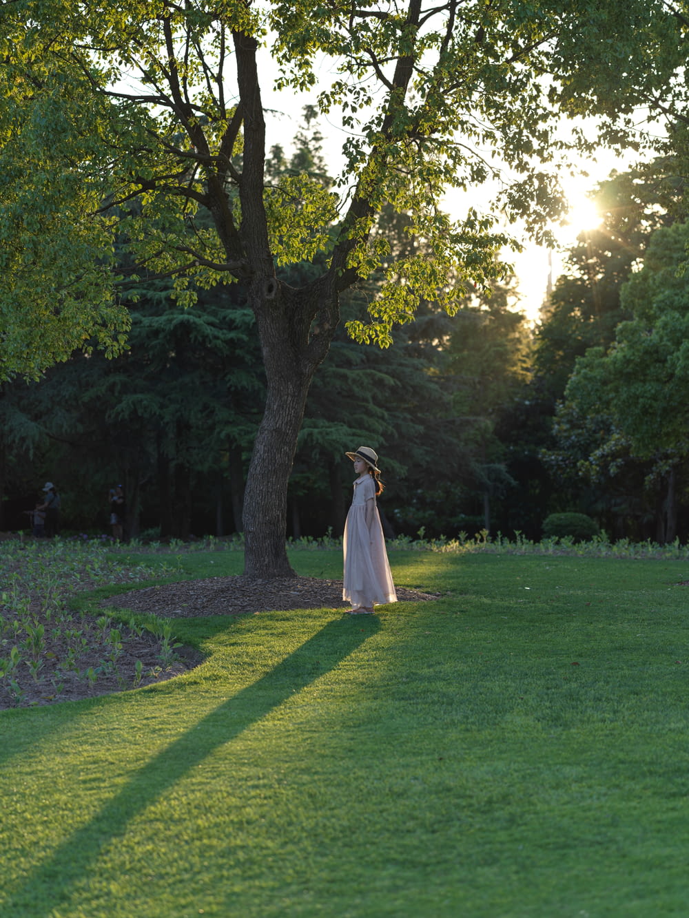 woman in white dress walking on green grass field during daytime