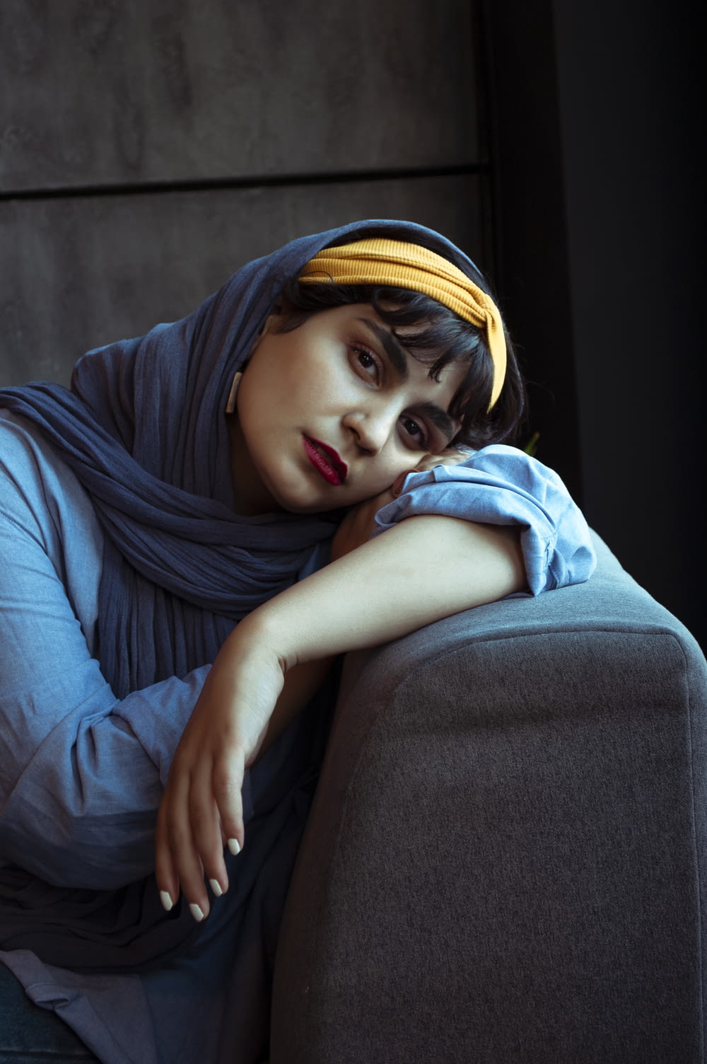 Donna in hijab blu seduta sul divano nero