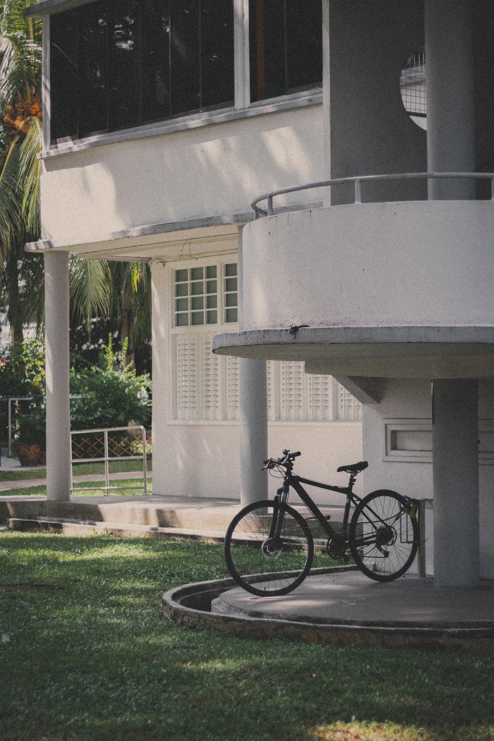 bicicleta preta estacionada ao lado do edifício de concreto branco durante o dia