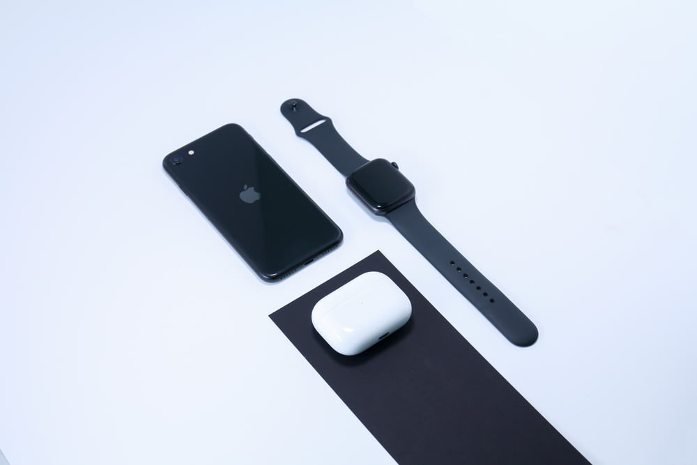 iPhone 7 noir à côté de l’Apple Watch avec bracelet sport blanc