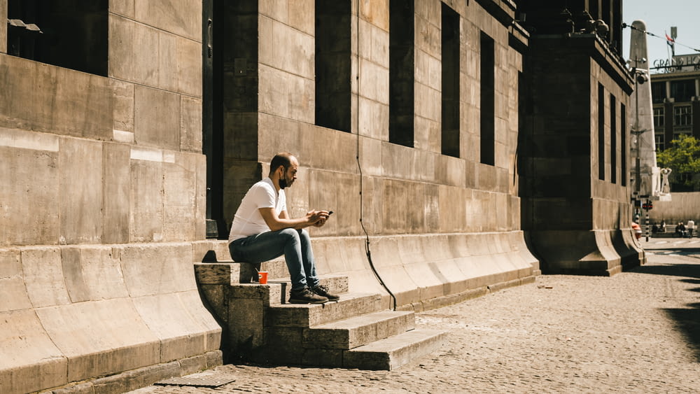 man in white t-shirt sitting on concrete bench