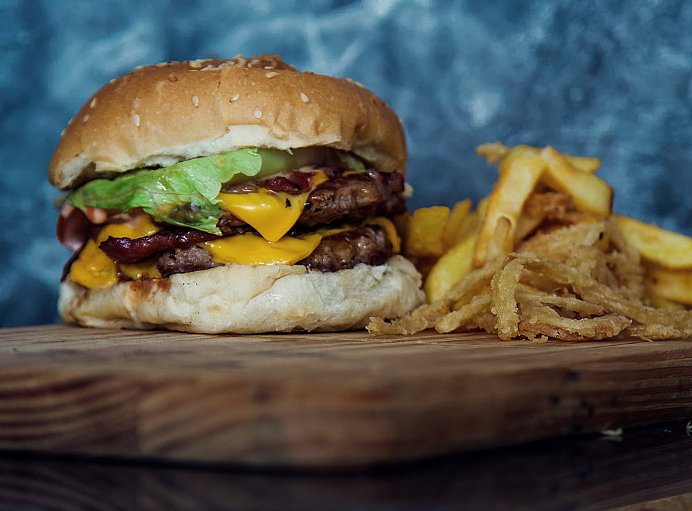 burger with lettuce and fries on brown wooden table