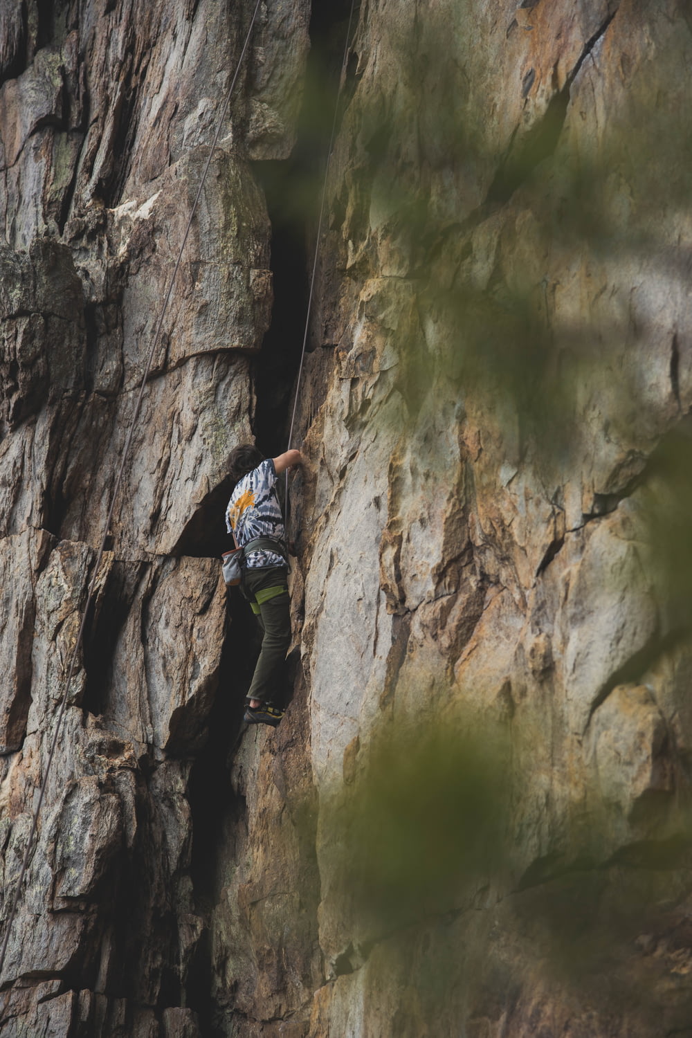 Mann in blauer Jacke klettert tagsüber auf braune Felsformation