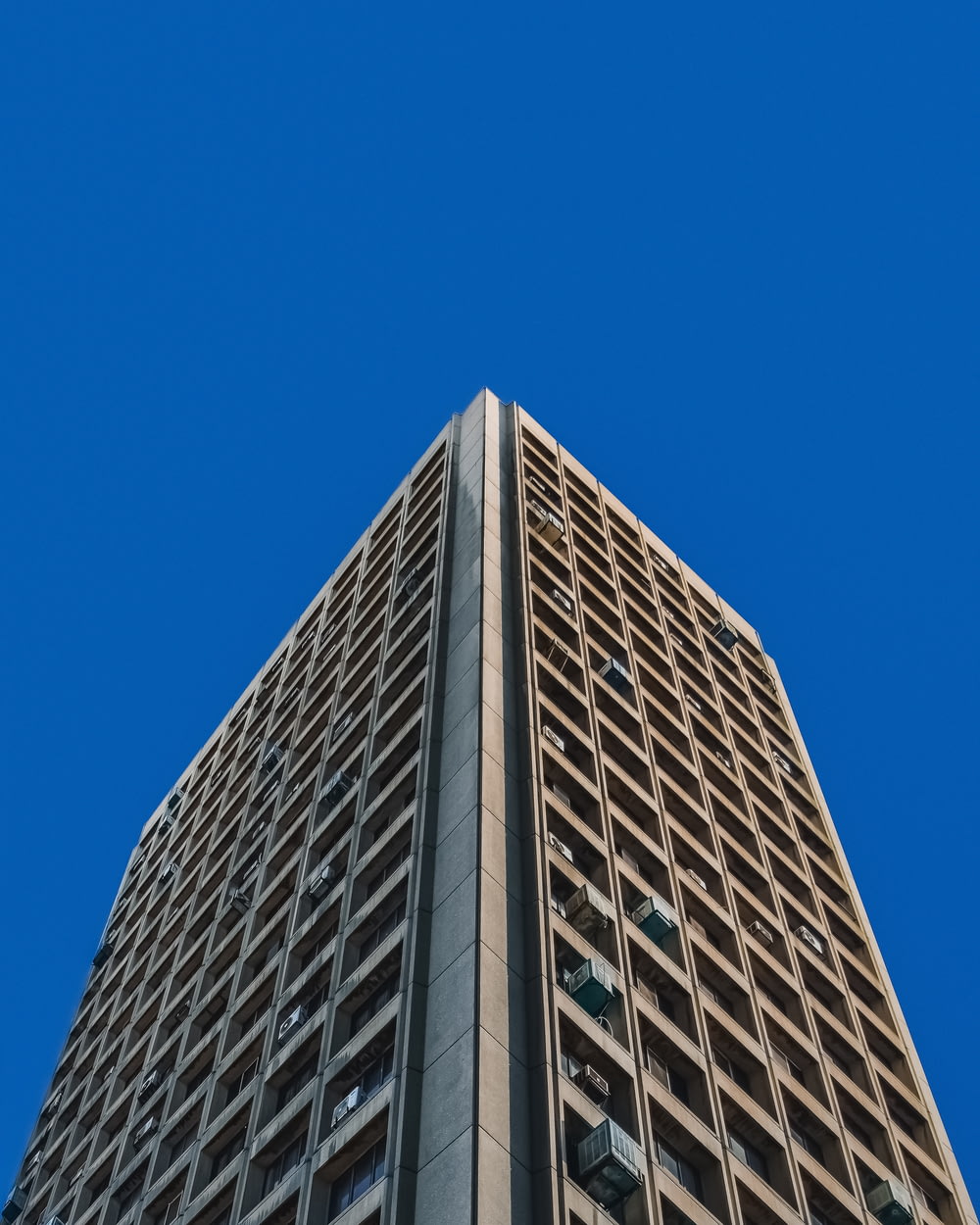 昼間の青空下の灰色のコンクリートの建物のローアングル写真