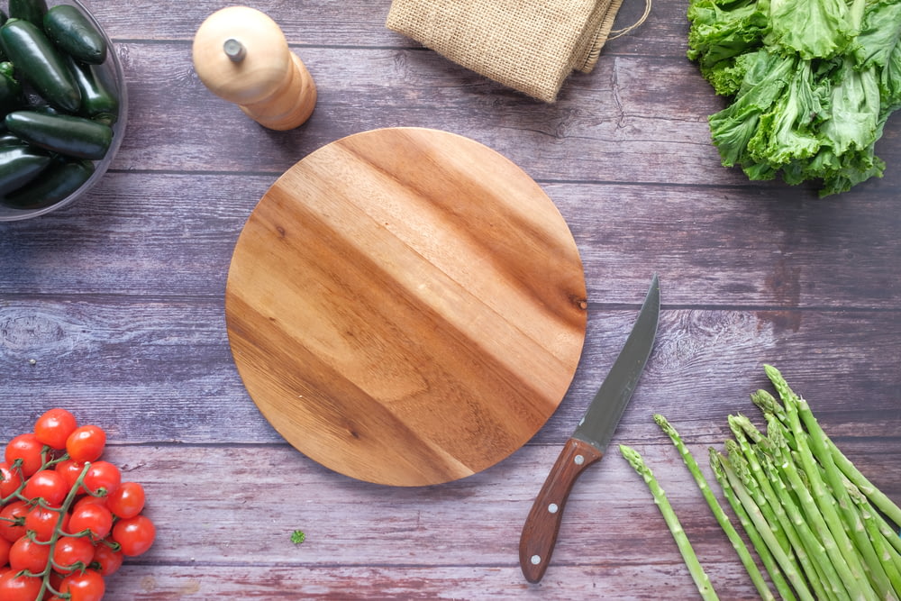 tabla de cortar de madera marrón junto a vegetal verde