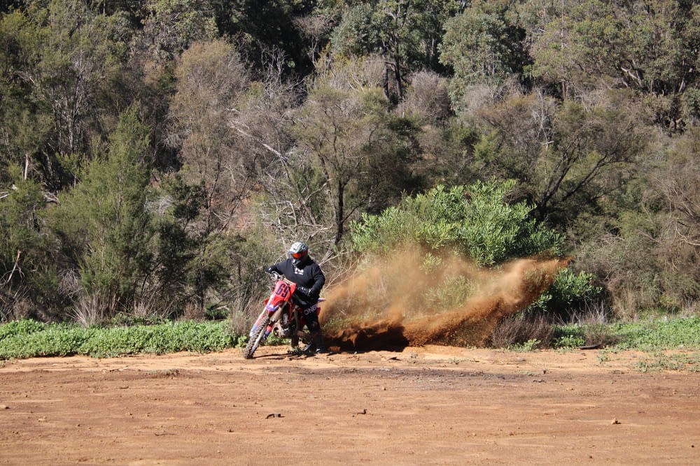 man riding motocross dirt bike on dirt road during daytime