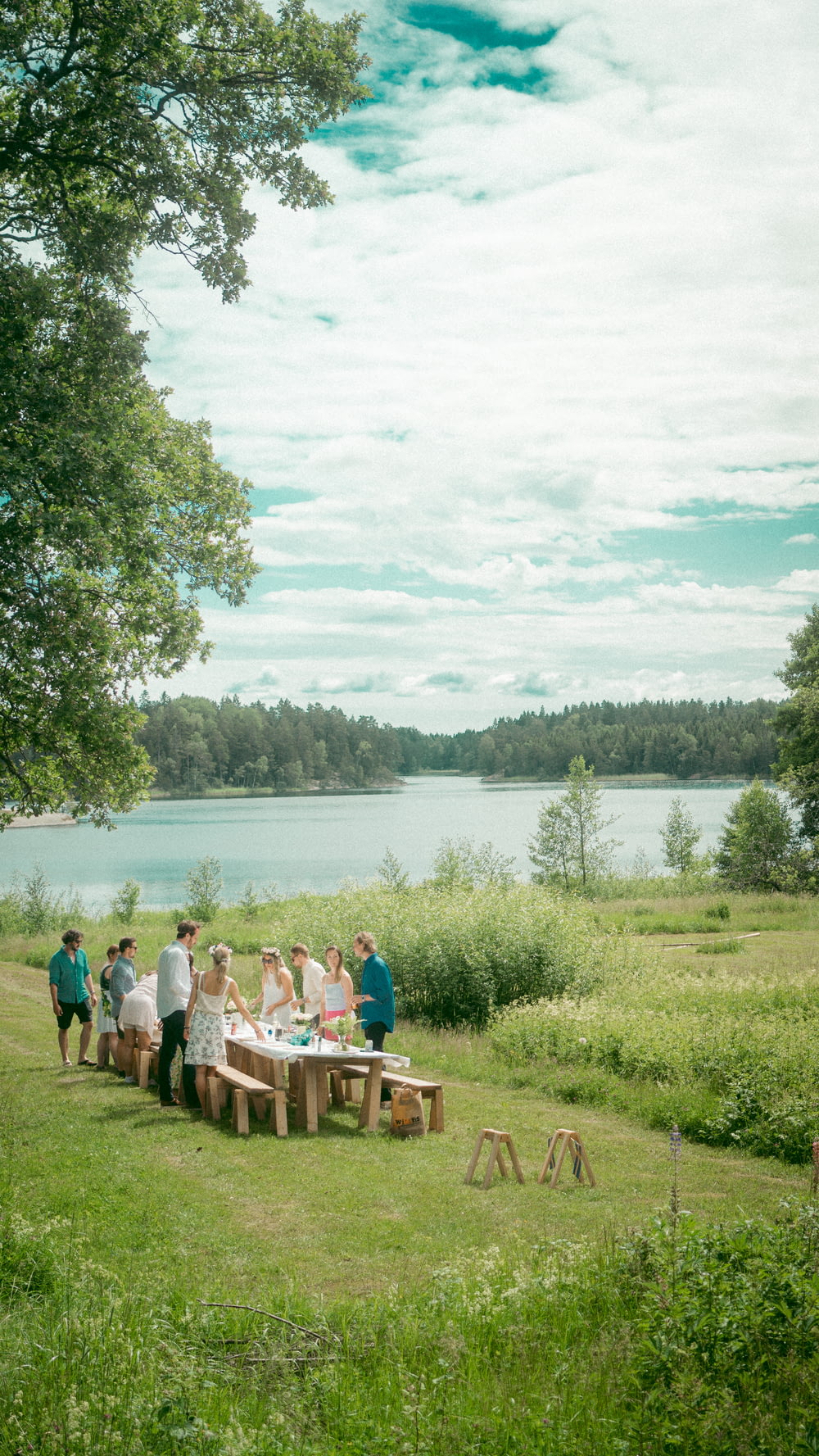 pessoas sentadas no banco de madeira marrom perto do lago durante o dia