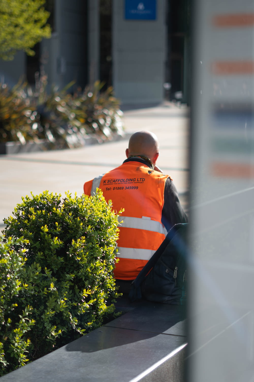 man in orange and black jacket standing near green plant during daytime