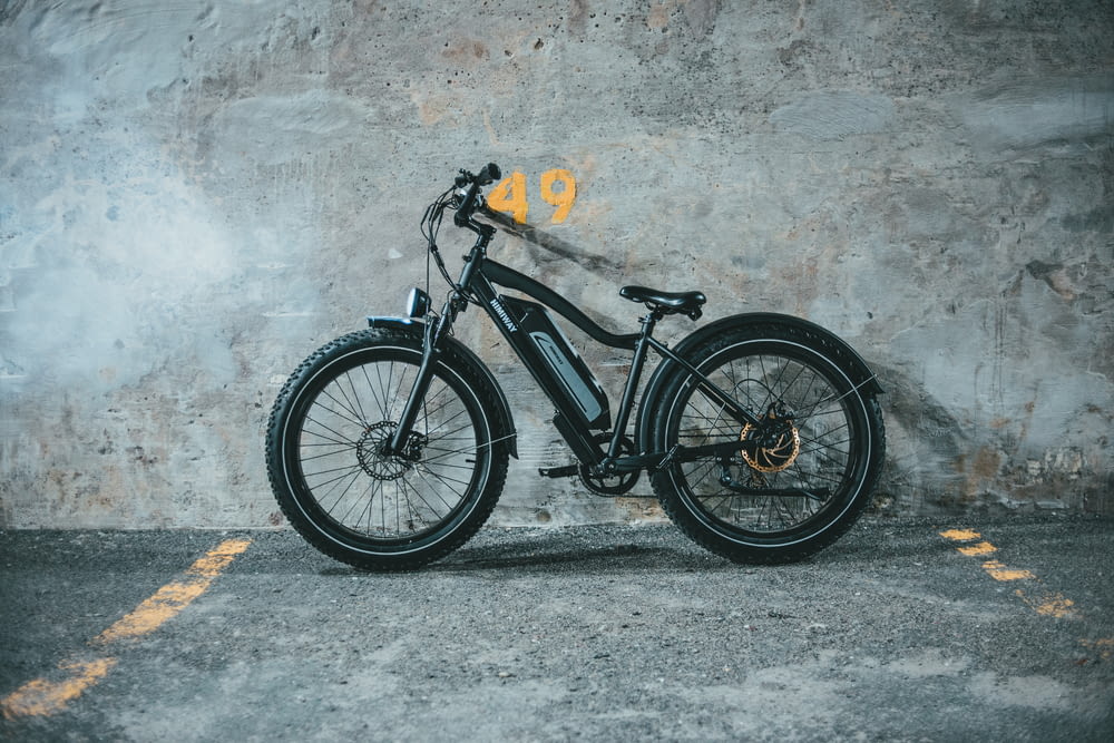 a black bicycle parked in front of a concrete wall