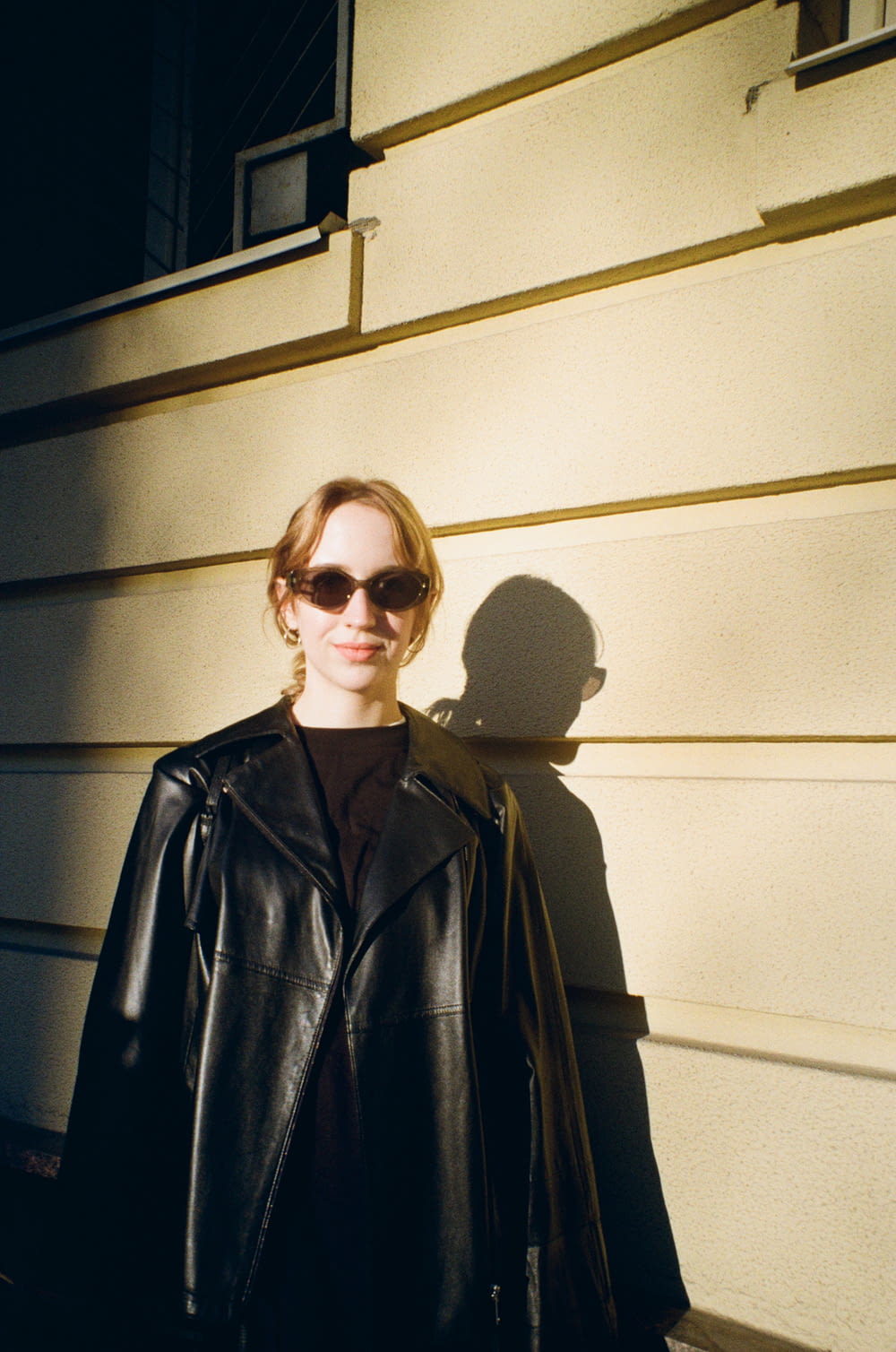 a woman in a black jacket and sunglasses standing in front of a building