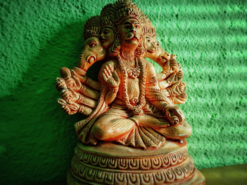 gold hindu deity figurine on green textile