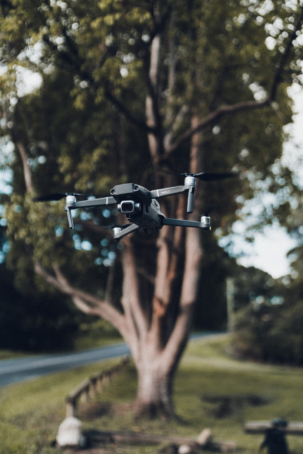 black drone flying over the green trees during daytime