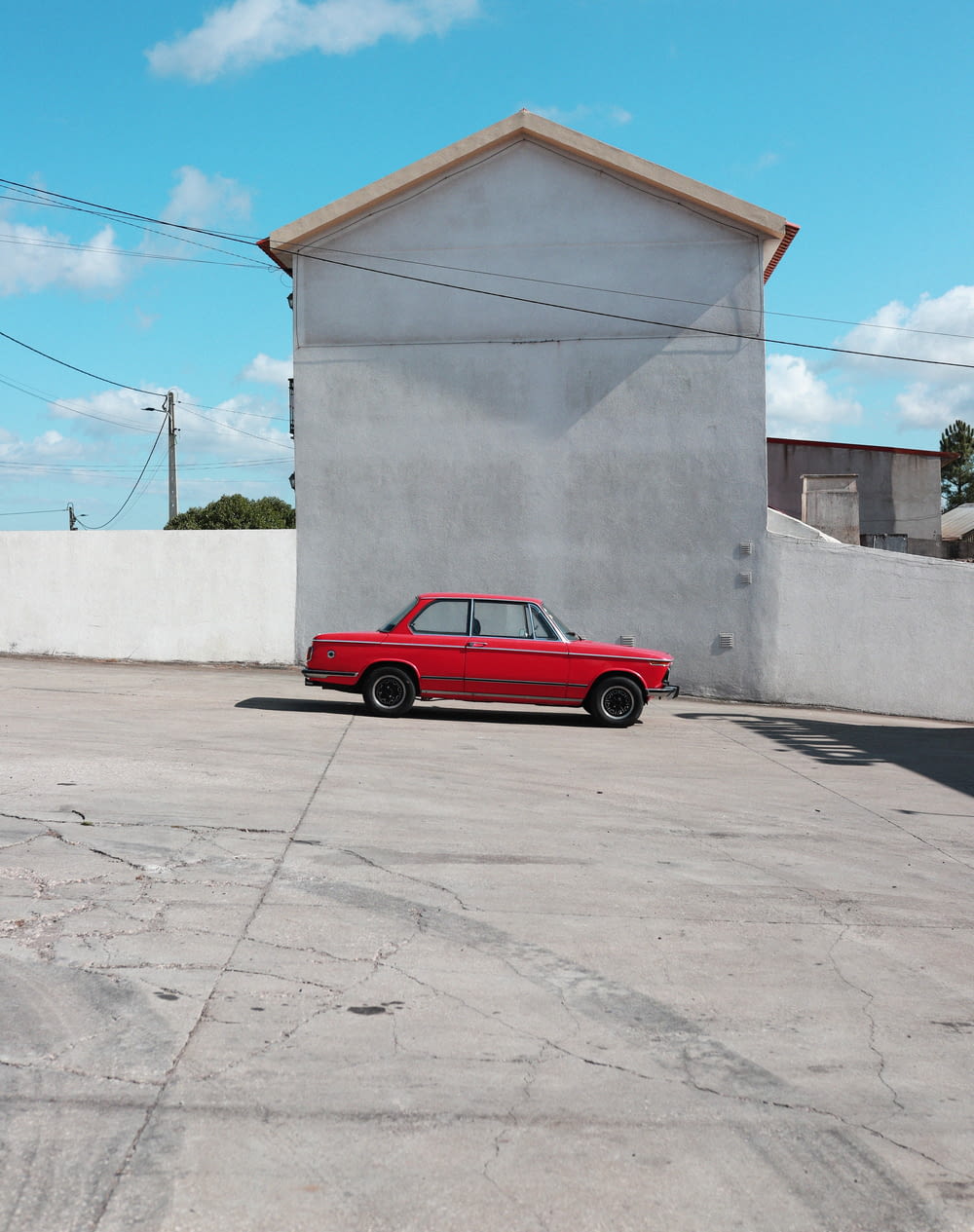 red coupe parked beside white wall