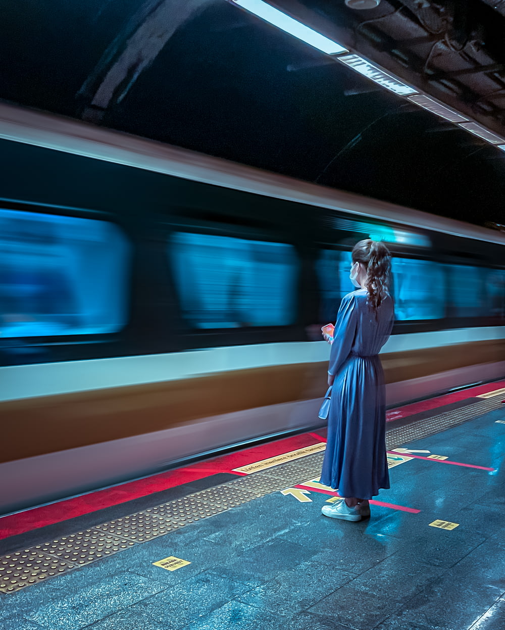 femme en robe bleue à manches longues debout sur la gare