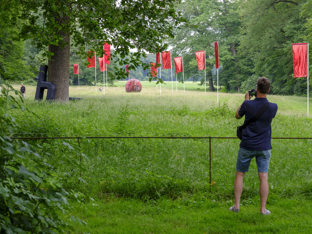 man in black shirt and blue denim shorts standing on green grass field