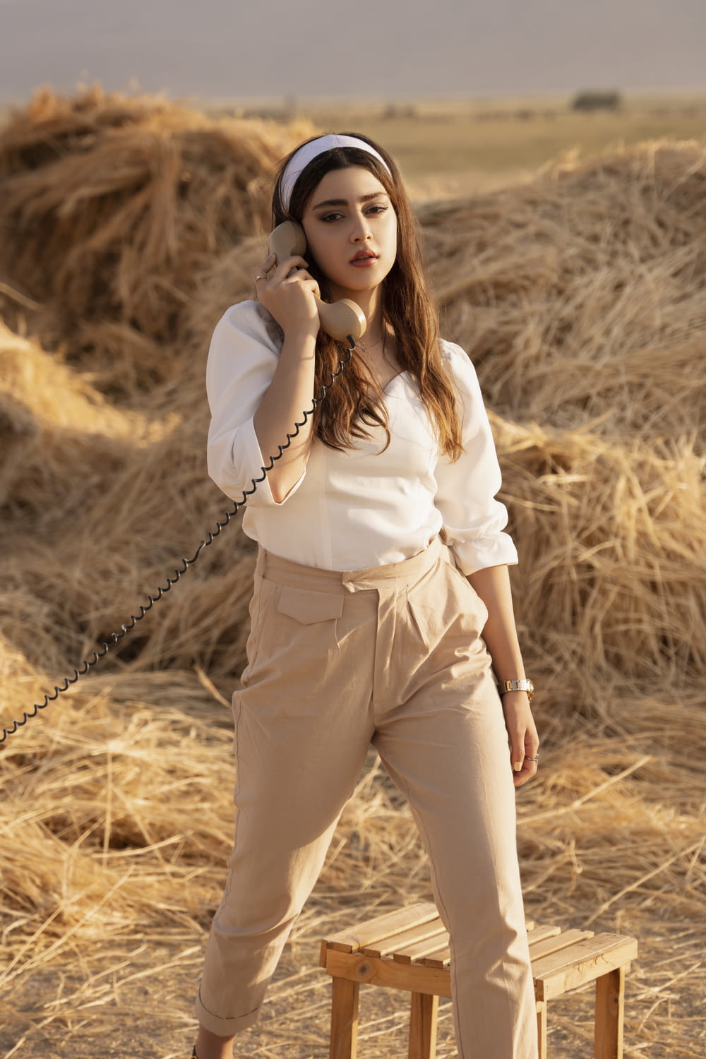 woman in white long sleeve shirt and white pants holding brown grass