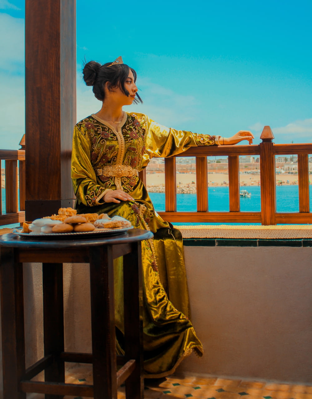 a woman in a golden dress sitting on a balcony