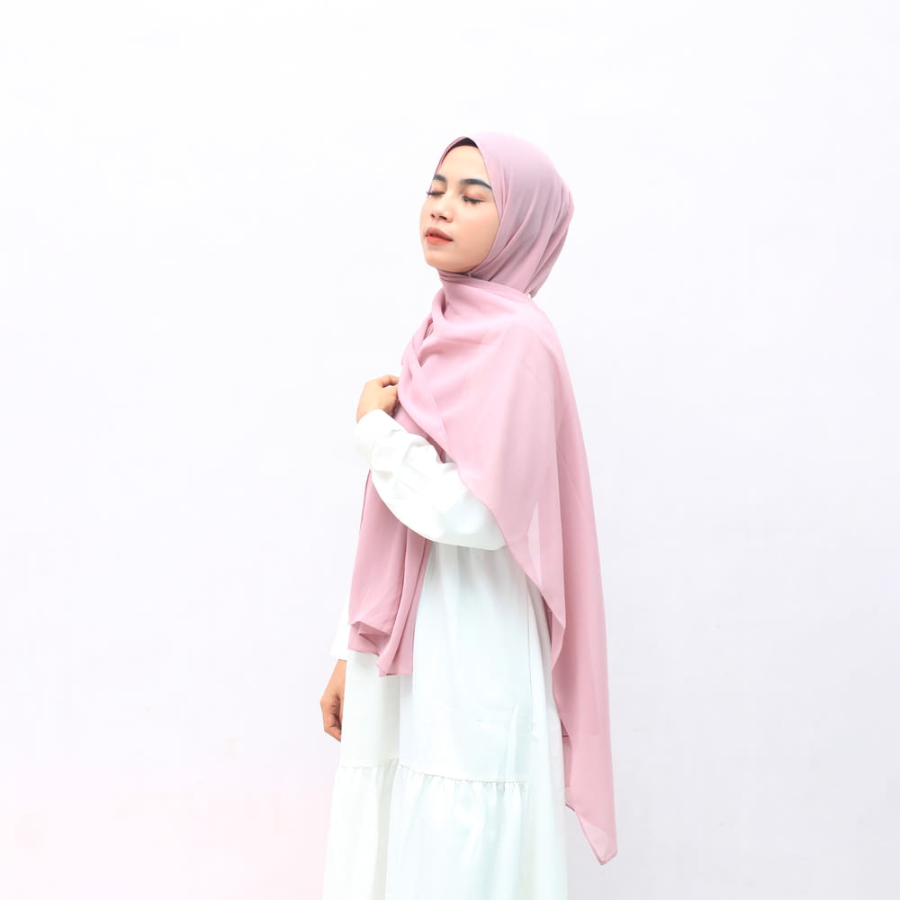 Frau in rosa Hijab und weißem langärmeligem Kleid