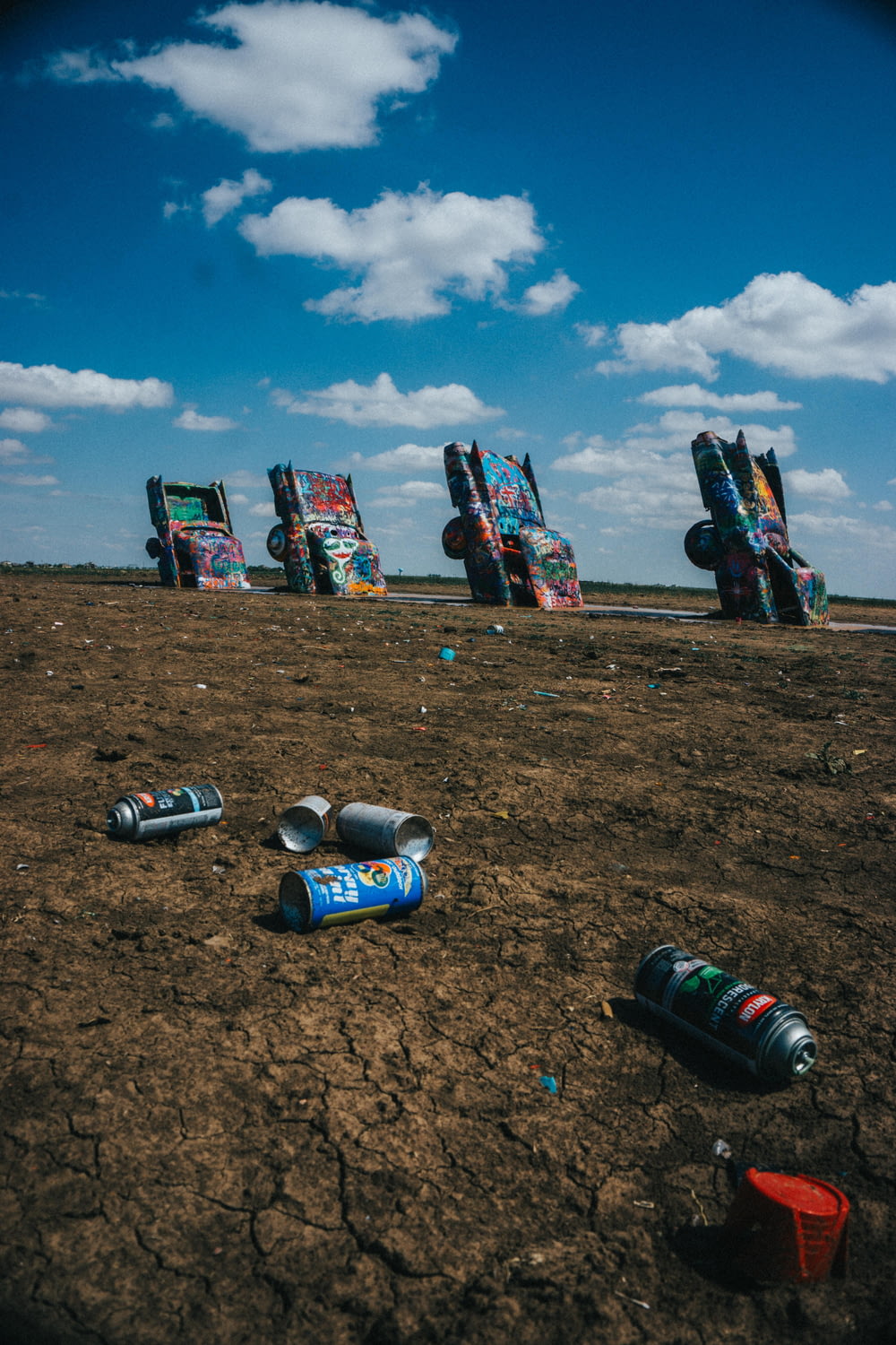 assorted cans on brown sand under blue sky during daytime