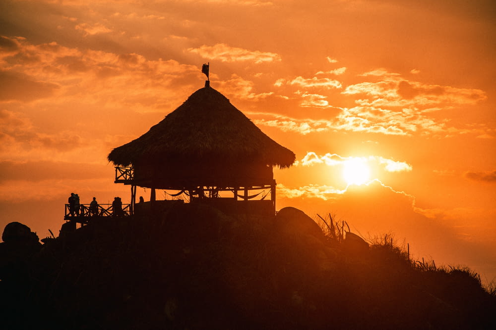 silhouette de personnes debout près du belvédère en bois brun pendant le coucher du soleil