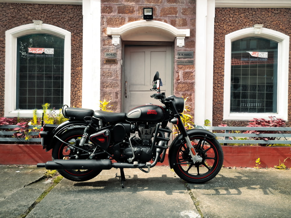 Motocicleta Cruiser negra y plateada estacionada junto a un edificio de concreto marrón durante el día