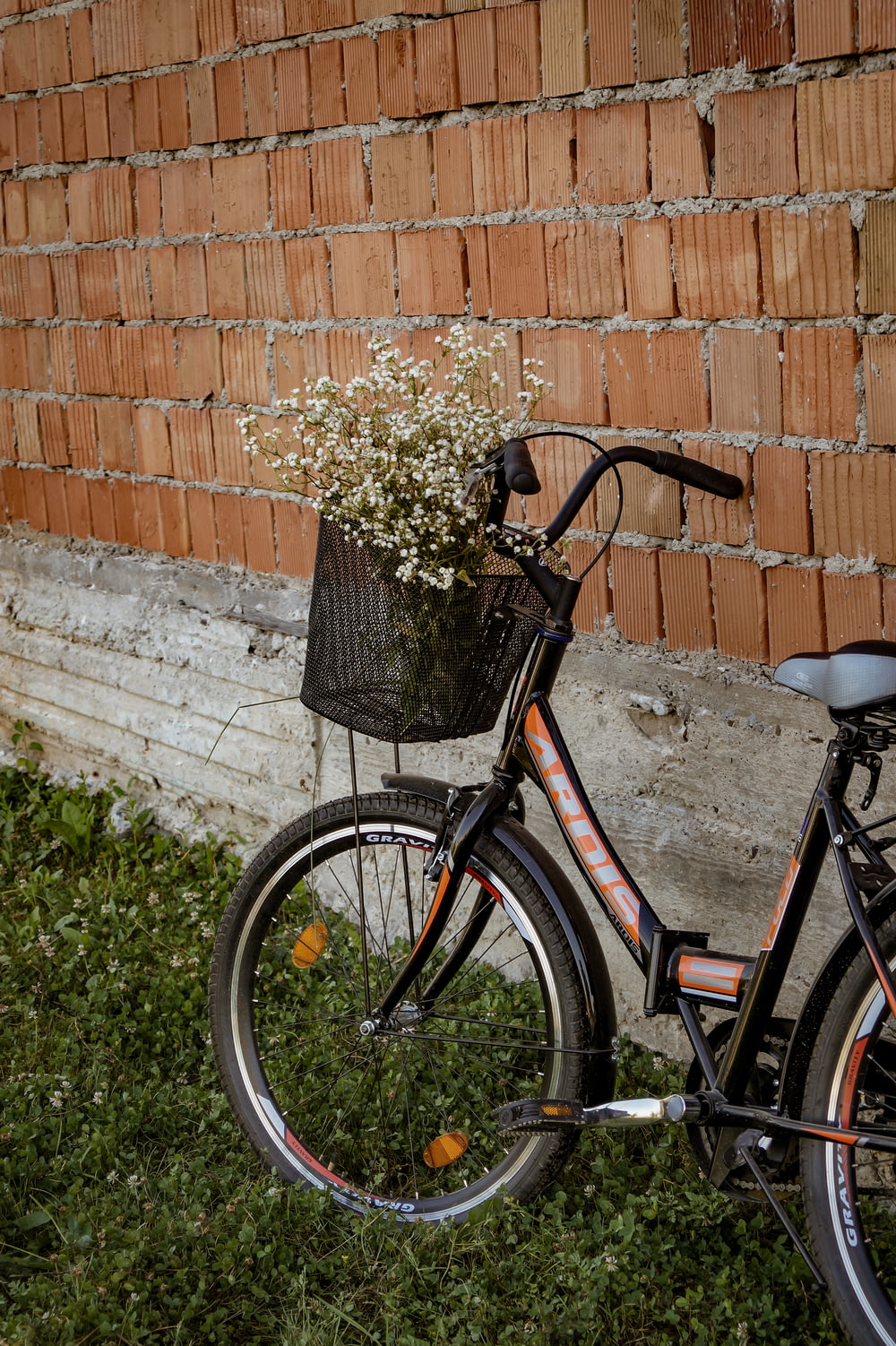 black city bike beside brown brick wall