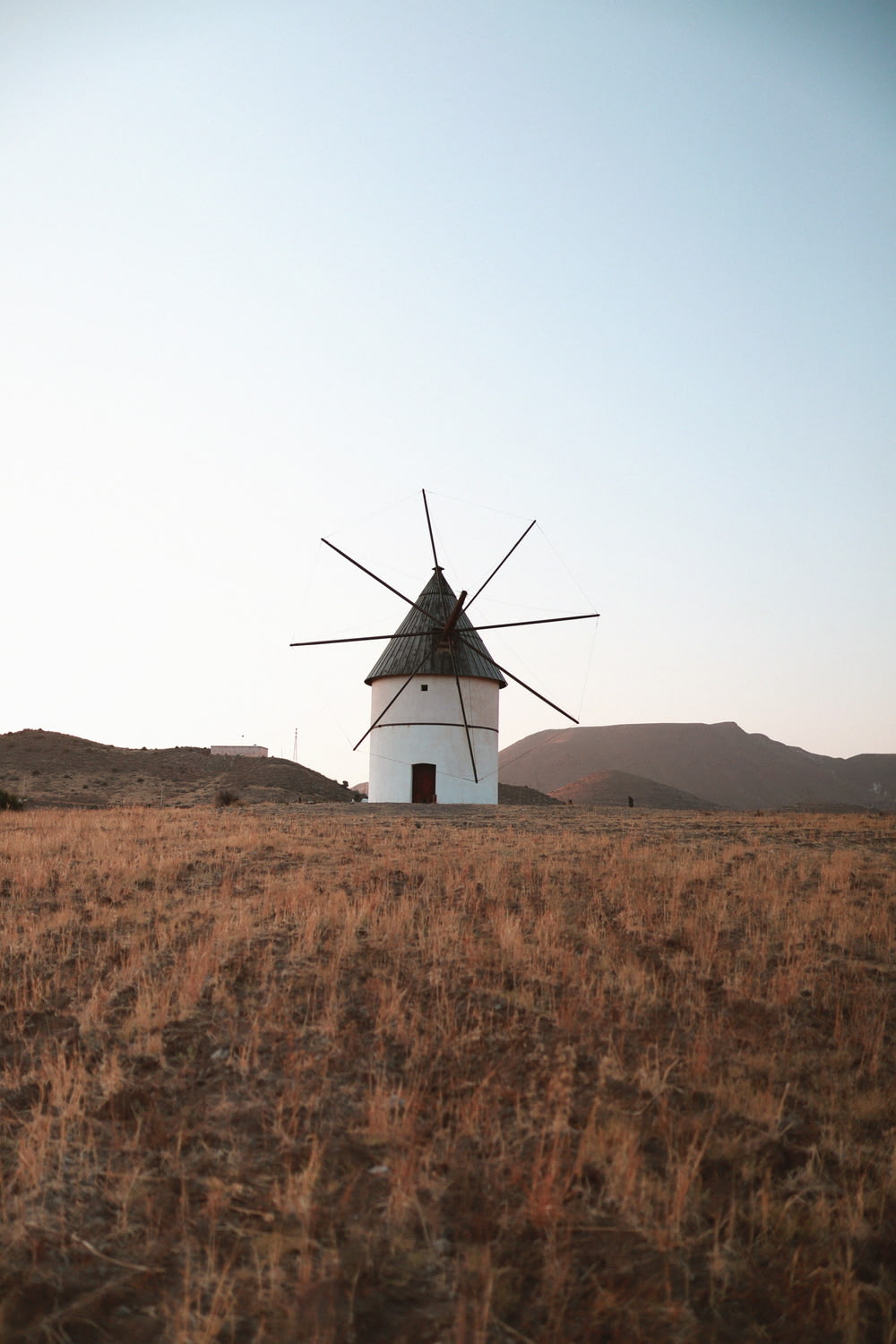 white and black windmill on brown field under white sky during daytime