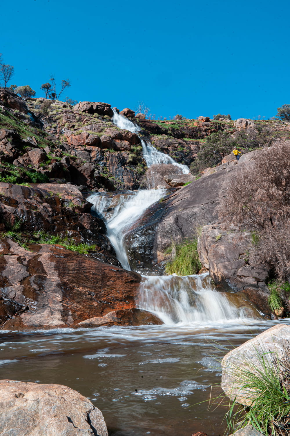 water falls on brown rocky mountain under blue sky during daytime