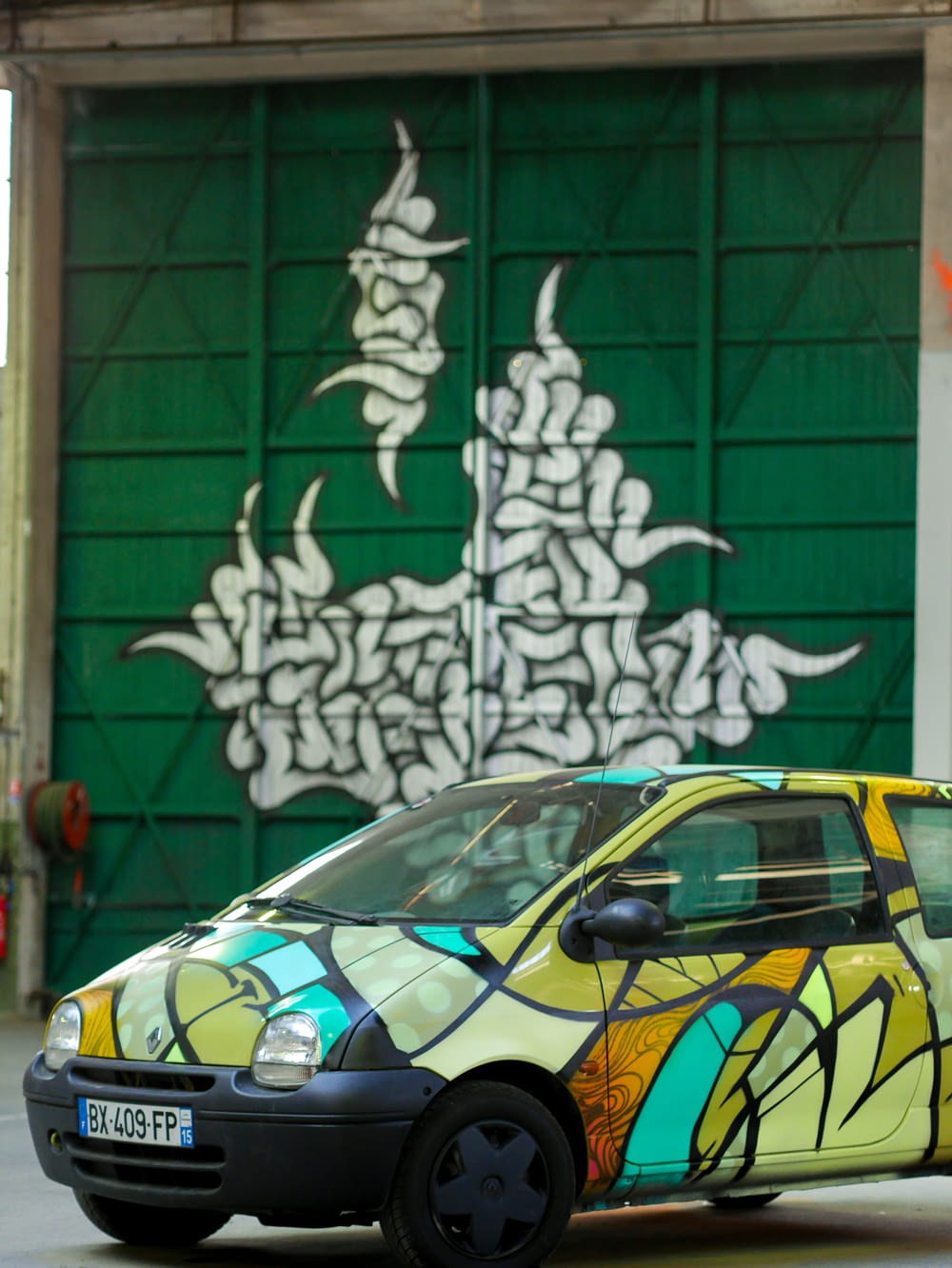 yellow and black car parked beside green and white wall